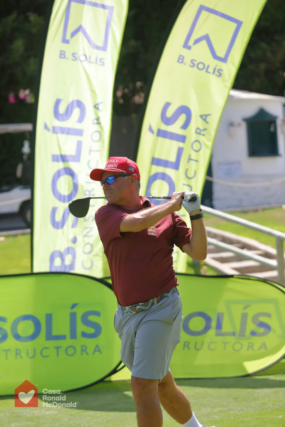 Participante en el torneo de golf solidario junto a las banderolas de Construcciones Bonifacio Solís en Guadalmina